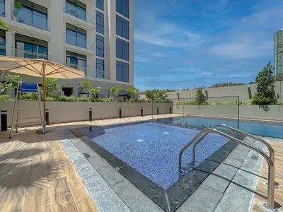 a swimming pool with an umbrella next to a building at Luxurious Nature with 5 Star Amenities in JVC in Dubai