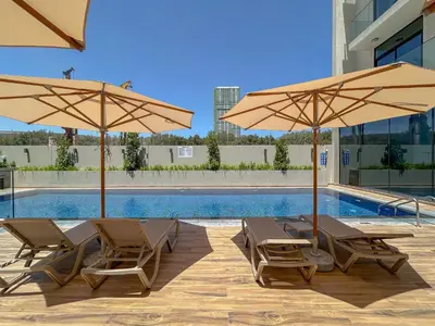 two chairs and two umbrellas next to a pool at Luxurious Nature with 5 Star Amenities in JVC in Dubai