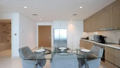 a dining room with a glass table and chairs in a kitchen at Luxury 2BR, Panoramic Sea Views and Beach Access in Dubai