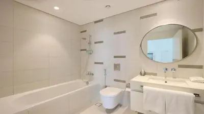 a bathroom with a tub sink and a toilet and a mirror at Luxury 2BR, Panoramic Sea Views and Beach Access in Dubai