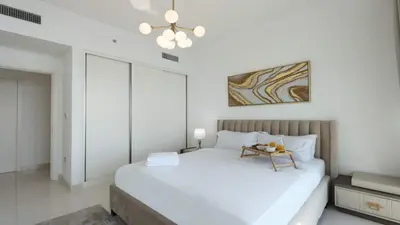 a white bedroom with a bed and a table at Luxury 2BR, Panoramic Sea Views and Beach Access in Dubai