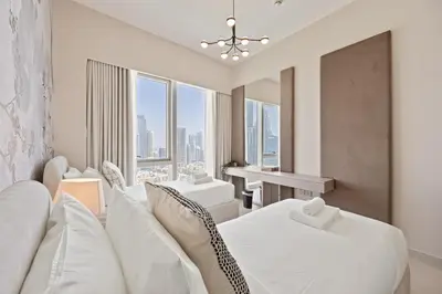 a living room with two beds and a desk and windows at Elite Escapes - 2 BHK Luxurious - Grande Signature in Dubai