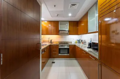 a kitchen with wooden cabinets and a stove top oven at Stand Point Residence by Hogar in Dubai