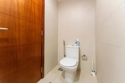 a bathroom with a toilet and a wooden door at Stand Point Residence by Hogar in Dubai