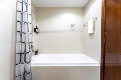 a white bathroom with a tub and a shower at Stand Point Residence by Hogar in Dubai