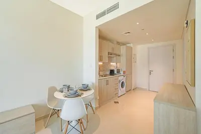 a kitchen with a table and chairs in a room at Spacious Studio Beach Access Seven Palm Dubai in Dubai