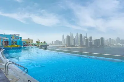 a large swimming pool with a view of a city at Spacious Studio Beach Access Seven Palm Dubai in Dubai