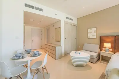 a living room with a bed and a table and chairs at Spacious Studio Beach Access Seven Palm Dubai in Dubai