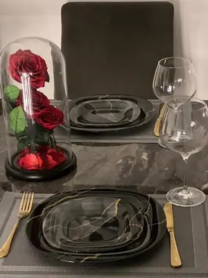 a table with black plates and red roses in a vase at Luxury 1BR Apartment with Burj Khalifa&Canal view in Dubai