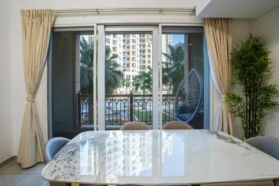 a dining room with a table and a large window at PJ- Premium Palm Jumeirah Apartment - Beachfront, Pool & Balcony in Dubai