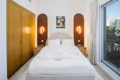a bedroom with a white bed and a large window at PJ- Premium Palm Jumeirah Apartment - Beachfront, Pool & Balcony in Dubai