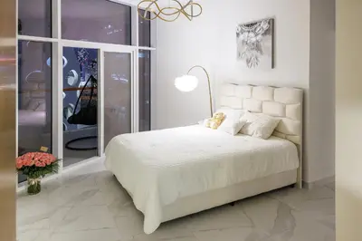 a bedroom with a white bed with a teddy bear on it at 5 Min Downtown in Dubai