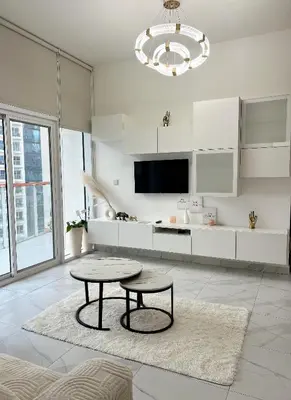 a white living room with a table and a tv at 5 Min Downtown in Dubai