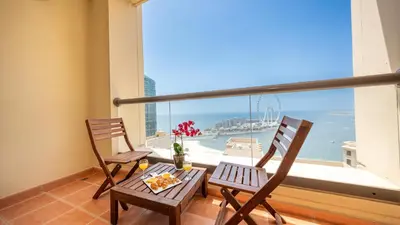 two chairs and a table on a balcony with a view of the ocean at Luxury Casa - Paramount Sea View Apartment 2BR in Dubai