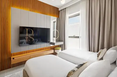 a living room with two white chairs and a tv at Lagoon Charm Luxurious Waterfront Living in Dubai