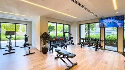 a gym with several exercise equipment in a room with windows at TRPS - Burj Royale, Downtown Dubai - 2BR - Burj Khalifa View - Furnished & Ready in Dubai