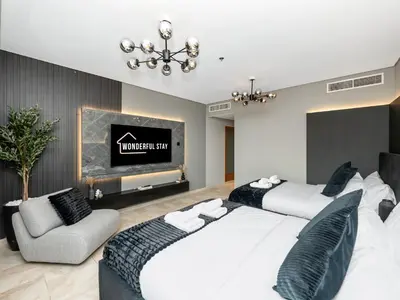 two beds in a room with a tv and a couch at WonderfulStay at Marine Towers - Full Ain & Marina View - JBR Grande Living - Brand New Apartments in Dubai