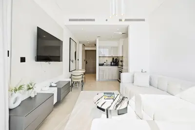 a white living room with a couch and a table at High-Floor Luxury Spacious 1BR in Sobha Waves in Dubai
