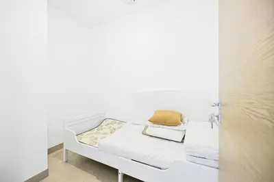 a white bed in a room with white walls at High-Floor Luxury Spacious 1BR in Sobha Waves in Dubai