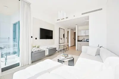 a white living room with a white couch and a tv at High-Floor Luxury Spacious 1BR in Sobha Waves in Dubai