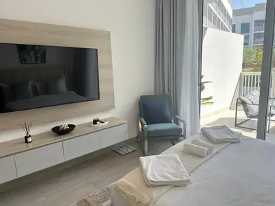 a bedroom with a television and a blue chair at Cosy Studio - Luma 22 in Dubai