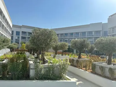 a garden with trees and plants in front of a building at Cosy Studio - Luma 22 in Dubai