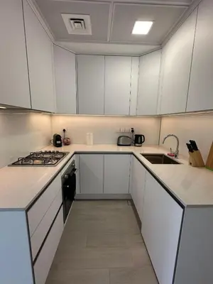 a kitchen with white cabinets and a stove top oven at Cosy Studio - Luma 22 in Dubai