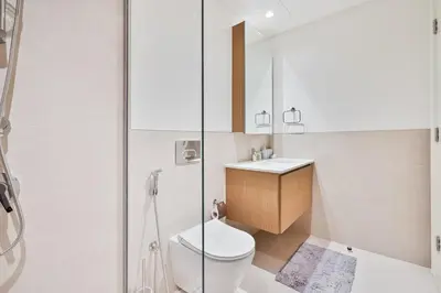 a bathroom with a toilet and a sink and a shower at Charming 1BR with Airy Terrace, Pool and Gym Access in Dubai