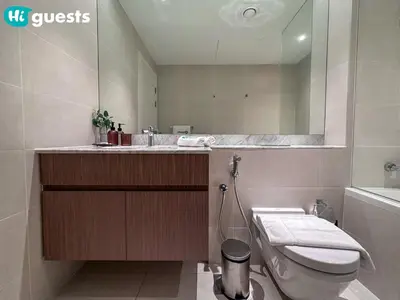 a bathroom with a sink and a toilet and a mirror at HiGuests - Soothing Seaside 2 BR Haven in La Mer in Dubai