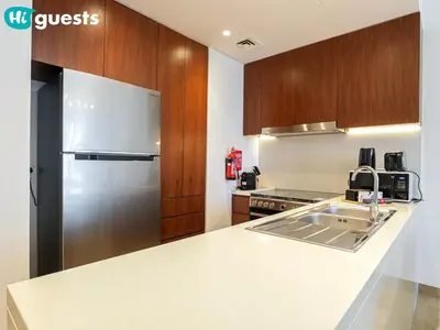 a kitchen with a stainless steel refrigerator and wooden cabinets at HiGuests - Soothing Seaside 2 BR Haven in La Mer in Dubai