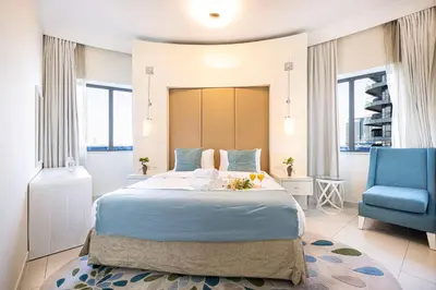 a bedroom with a large bed and a blue chair at Damac Maison Mall Street! 2 Bedroom, 1-minute to Dubai Mall! in Dubai