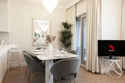 a dining room with a table with chairs and a television at Damac Maison Mall Street! 2 Bedroom, 1-minute to Dubai Mall! in Dubai