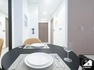 a black table with two white plates and wine glasses at Charming Studio with Balcony in Azizi Riviera in Dubai