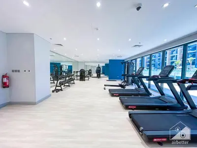 a gym with a row of treadmills and machines at Charming Studio with Balcony in Azizi Riviera in Dubai