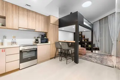 a kitchen with wooden cabinets and a table with chairs at Miami Vibes | Canal View | Fully Furnished Studio in Dubai
