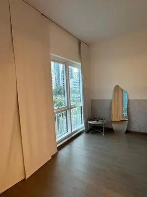 an empty room with a large window and a chair at Cozy Studio Apartment in Dubai