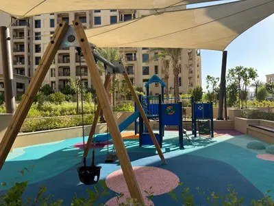 a playground with a swing set and an umbrella at Brand new apartment next to Burj Al Arb in Dubai