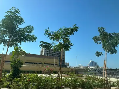 a view of a building with trees in the foreground at Brand new apartment next to Burj Al Arb in Dubai