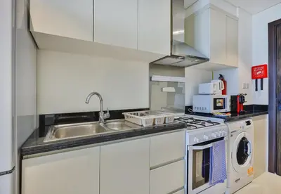 a white kitchen with a sink and a stove at Carson Tower B,Damac Hills - Studio Apartment - Allsopp & Allsopp in Dubai