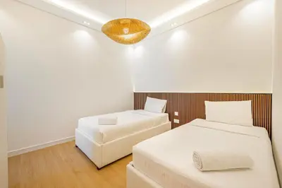 a bedroom with two beds and a light fixture at Daniels 3BR with Palm View at Marina Pinnacle in Dubai