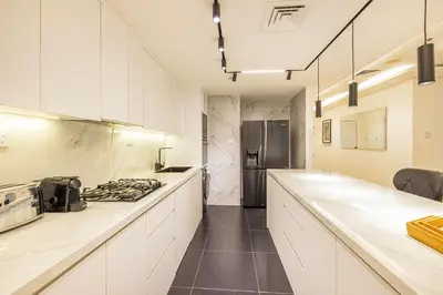 a kitchen with white counter tops and a refrigerator at Daniels 3BR with Palm View at Marina Pinnacle in Dubai