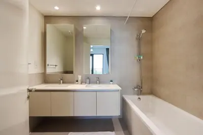 a bathroom with a sink and a tub and a mirror at Livbnb-Elegant 2BR, Creek Beach, Pool & Gym in Dubai