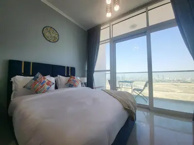 a bedroom with a large bed with a clock on the wall at DVR Studio apartment available in Damac Hills in Dubai