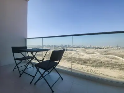 a table and two chairs in a room with a large window at DVR Studio apartment available in Damac Hills in Dubai