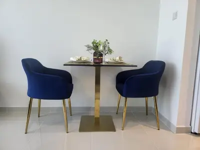 a dining table with two blue chairs and a table at DVR Studio apartment available in Damac Hills in Dubai
