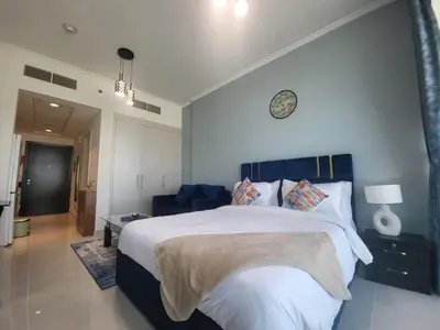a bedroom with a large bed with a clock on the wall at DVR Studio apartment available in Damac Hills in Dubai
