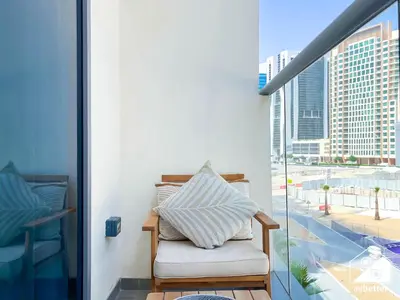 a chair on a balcony with a view of a city at Luxury at Sterling East Studio with Park Views in Dubai