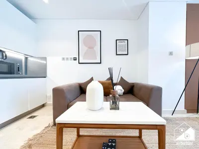 a living room with a couch and a table at Luxury at Sterling East Studio with Park Views in Dubai