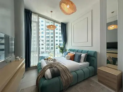 a bedroom with a green couch and a large window at Sunsets and Skylines 1BR in Panoramic Tower in Dubai