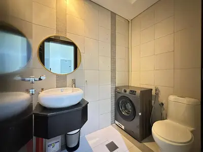 a bathroom with a sink and a washing machine at Sunsets and Skylines 1BR in Panoramic Tower in Dubai